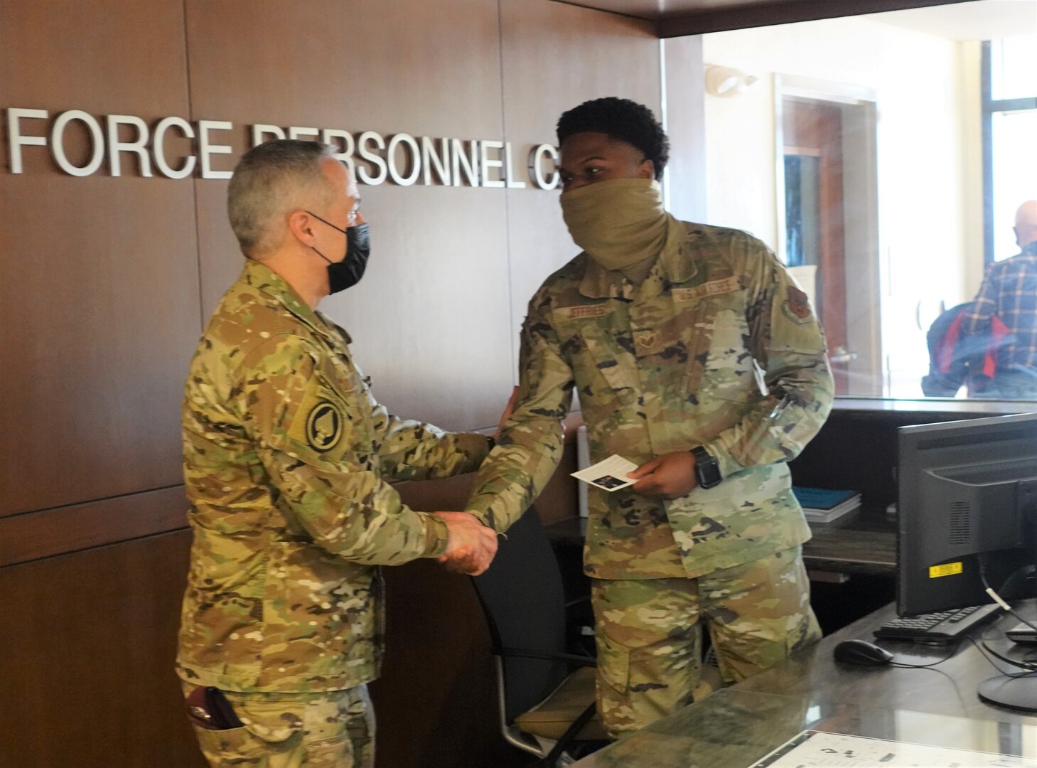 Senior military leader presenting coin to another military member.