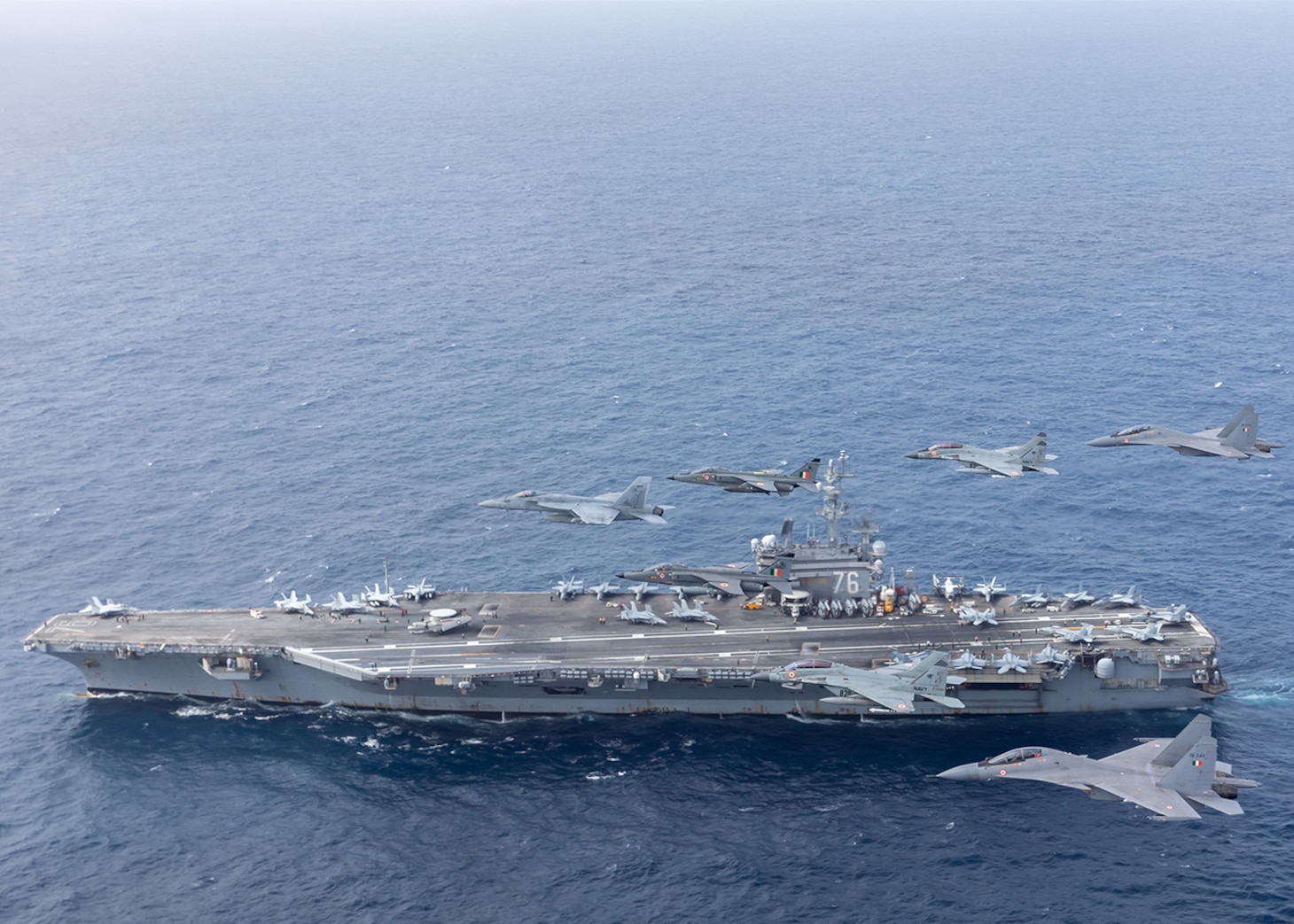 INDIAN OCEAN (June 23, 2021) Aircraft assigned to Carrier Air Wing (CVW) 5 and Indian air force aircraft fly in formation over the U.S. Navy’s only forward-deployed aircraft carrier, USS Ronald Reagan (CVN 76). Ronald Reagan, the flagship of Carrier Strike Group 5, provides a combat-ready force that protects and defends the United States, as well as the collective maritime interests of its allies and partners in the Indo-Pacific region. (Official U.S. Navy file photo)