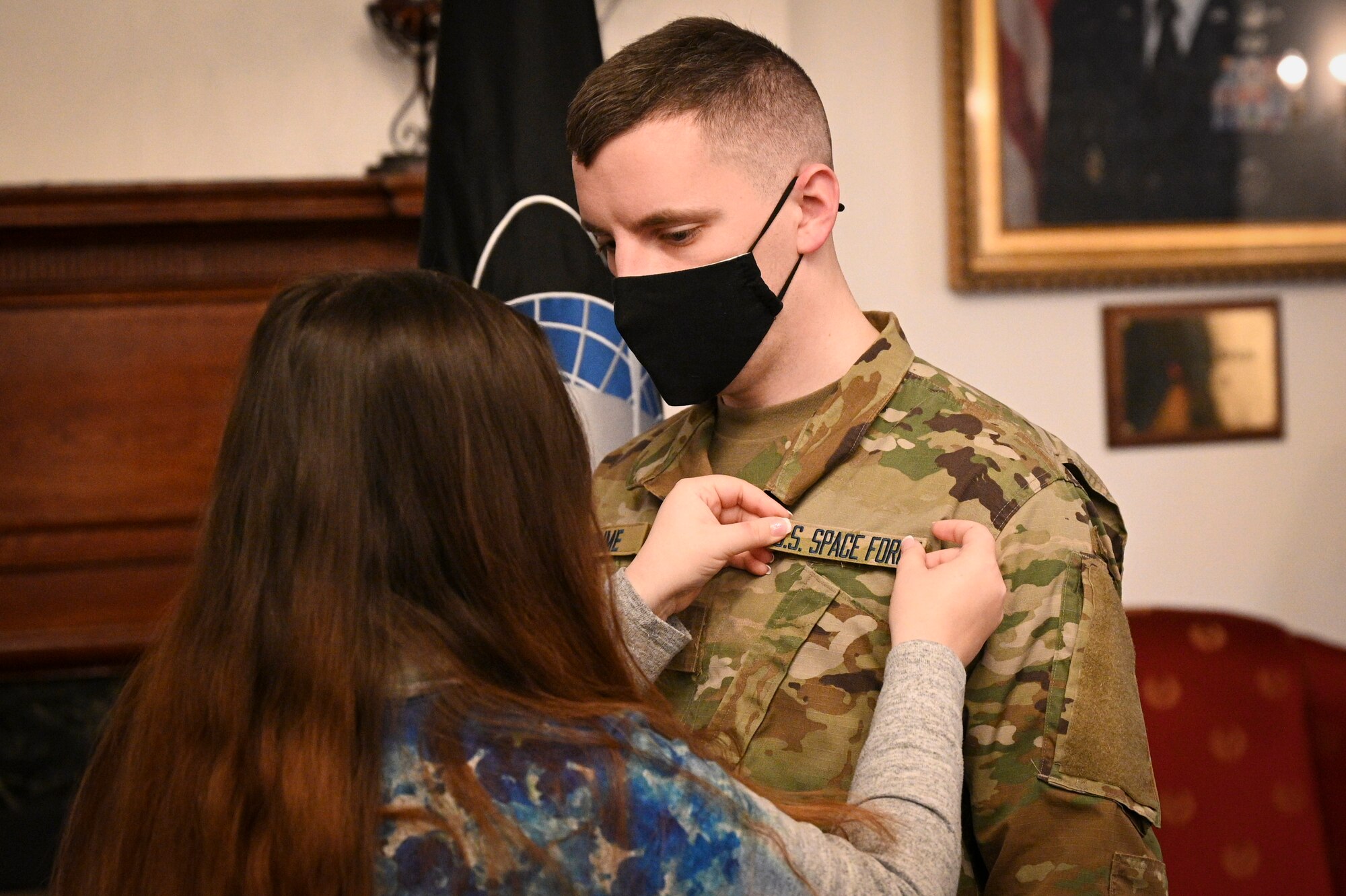 U.S. Army Sgt. Harly D. Gomme, White House Communications Agency satellite communications systems operator, has U.S. Space Force patches placed on his uniform by his wife, Tiffany, during his inter-service transfer ceremony.