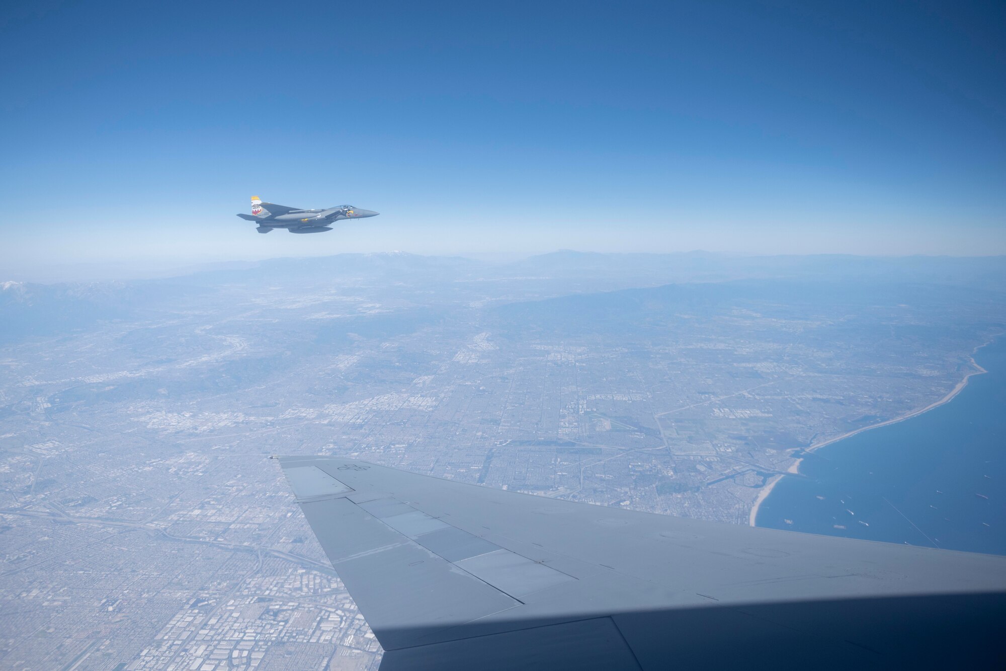 An F-15E Strike Eagle assigned to the 144th Fighter Wing, flies alongside a KC-10 Extender assigned to the 60th Air Mobility Wing, after receiving fuel Feb. 13, 2022, above Los Angeles. A KC-10 Extender provides 83,000 pounds of fuel to three F-15E Strike Eagles over the course of Super Bowl LVI, so they can provide security. (U.S. Air Force photo by Senior Airman Cameron Otte)