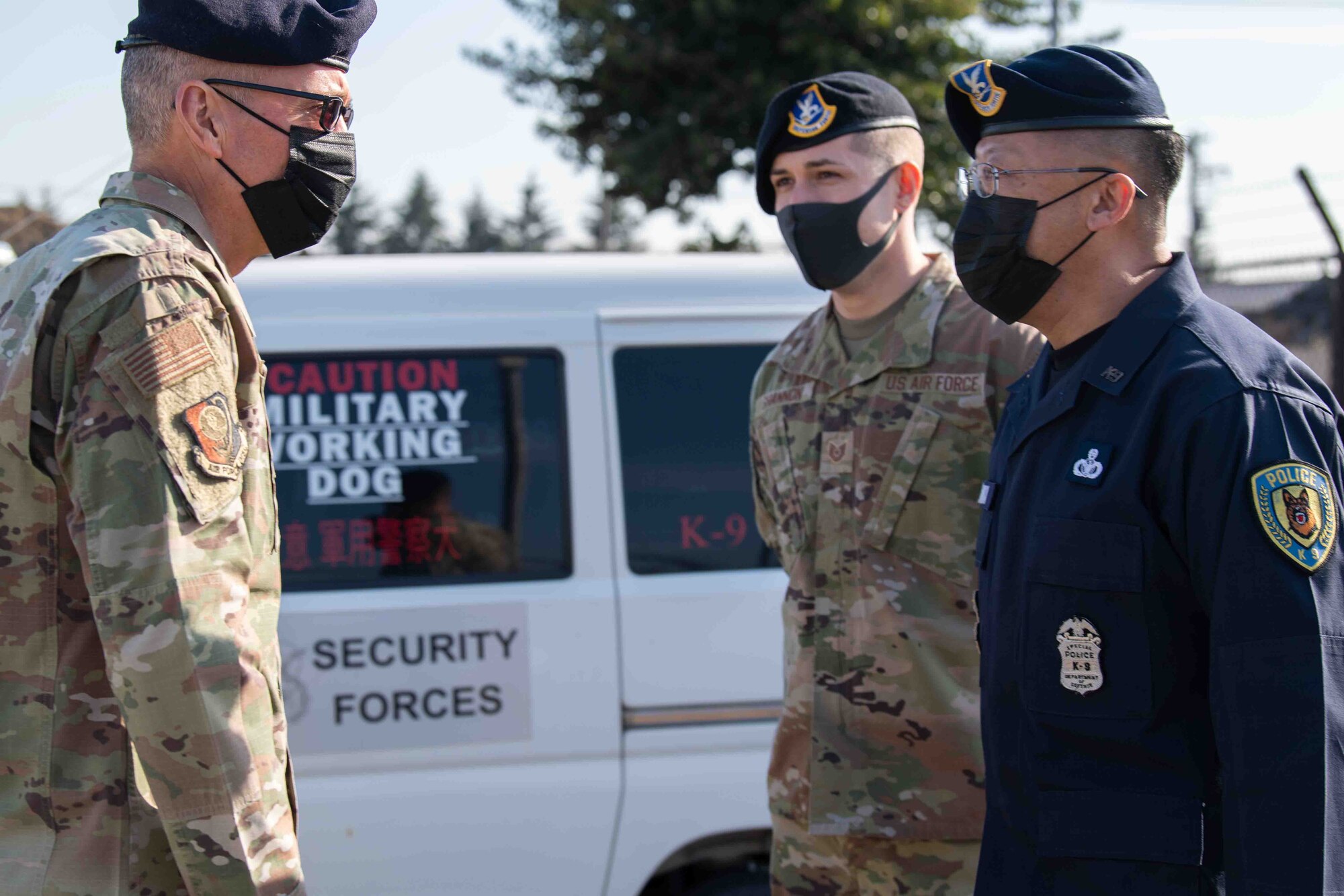 Tech. Sgt. Seth Shannon, center, 374th Security Force Squadron kennel master, and Naokazu Tajika, right, 374th SFS military working dog trainer, greet Maj. Gen. Tom Wilcox, Air Force Installation and Mission Support Center commander, at the MWD kennels during a site visit at Yokota Air Base, Japan, Feb. 9, 2022.