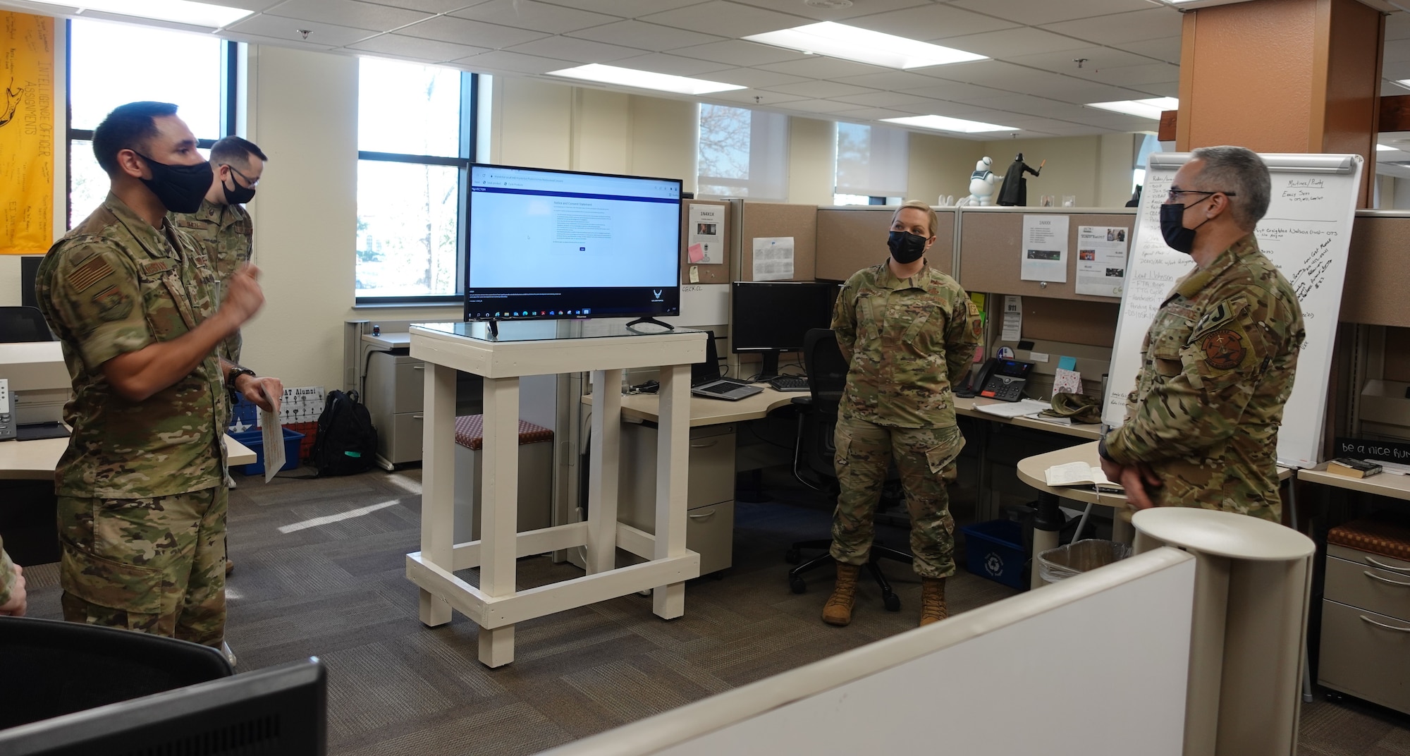 Three military members discussing Air Force assignments in work environment.