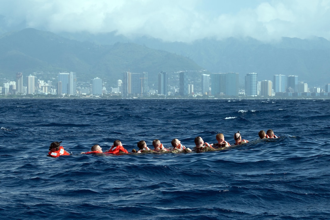 Airmen swim in a chain formation off the coast of Honolulu.