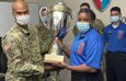 Army Lt. Col. Oliver Davis, the executive officer for the 405th Army Field Support Brigade, presents a trophy to Staff Sgt. Rebecca Aremu, the administration noncommissioned officer in charge of the 55th Quartermaster Company, 16th Sustainment Brigade, 21st Theater Sustainment. Aremu accepted the award Feb. 14 on behalf of her 55th QM Co. team, who manages and operates the Defender Café Warrior Restaurant on Rhine Ordnance Barracks in Kaiserslautern, Germany. The Defender Café Warrior Restaurant is the 2021 Europe Philip A. Connelly Military Garrison Award Competition winner and will next represent U.S. Army Europe and Africa in the 54th Annual Department of the Army Philip A. Connelly Competition. (U.S. Army courtesy photo)