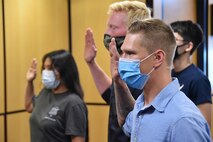 People raising right hand completing oath of enlistment.