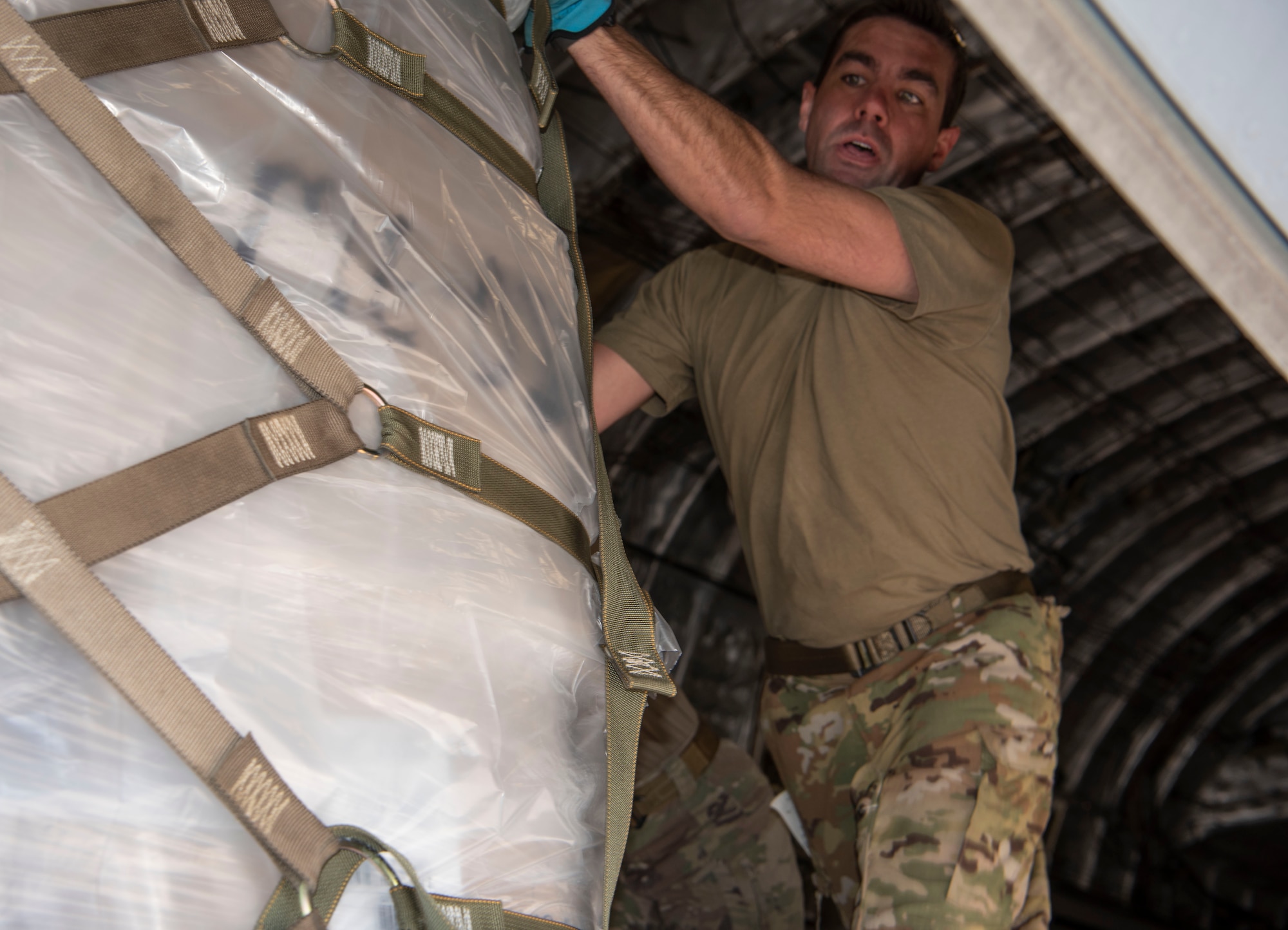 Master Sgt. Javier Lopez, loadmaster with Joint Base Charleston's Air Force Reserve 317th Airlift Squadron, offloads palletized medical supplies and food from the rear of a C-17 Globemaster III cargo aircraft at Soto Cano Air Base, Honduras, Feb. 13, 2022.  The cargo was donated by charities within the U.S. and was transported as part of the Denton Cargo Program, which allows for humanitarian goods to be transported aboard U.S. military aircraft on a space-available basis. (U.S. Air Force photo by Lt. Col. Wayne Capps)