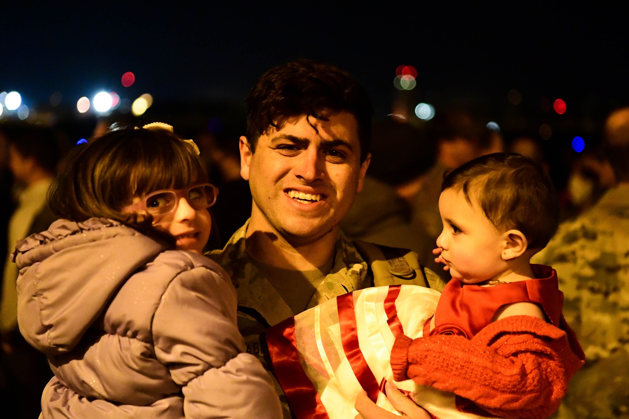 A U.S. Air Force Airman assigned to the 56th Rescue Squadron poses for a photo with his family after returning from a deployment, at Aviano Air Base, Italy, Feb. 9, 2022. The 56th RQS provides a rapidly-deployable, worldwide combat rescue and reaction force response utilizing HH-60G Pave Hawk helicopters. (U.S. Air Force photo by Senior Airman Noah Sudolcan)