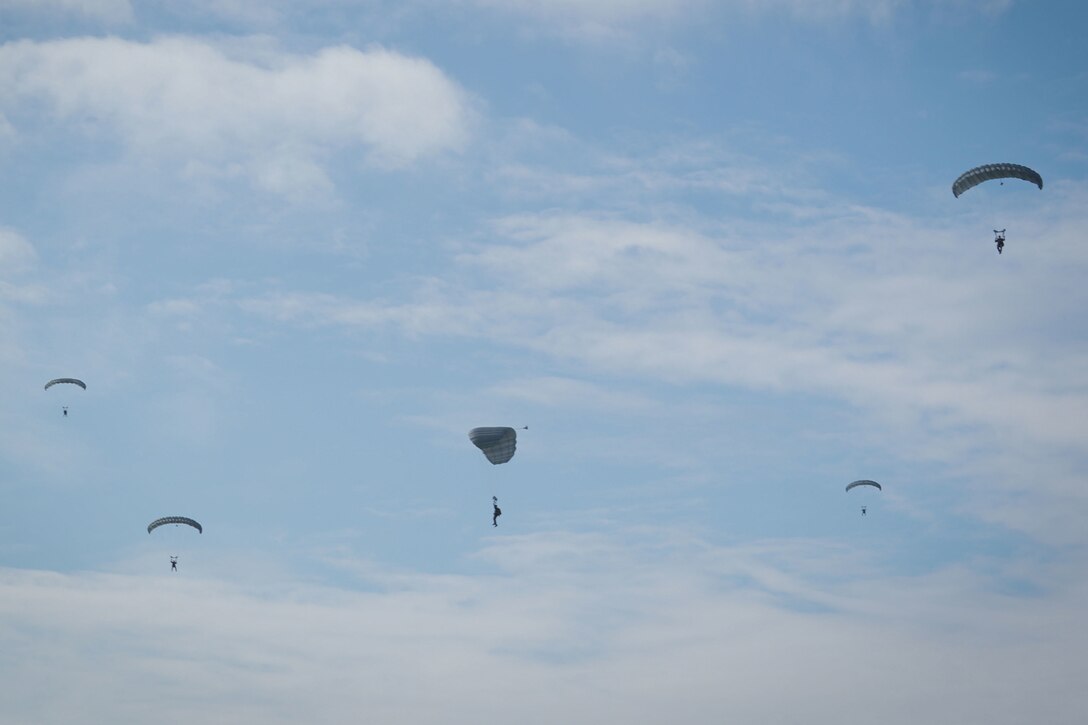 Marines parachute down to the ground.