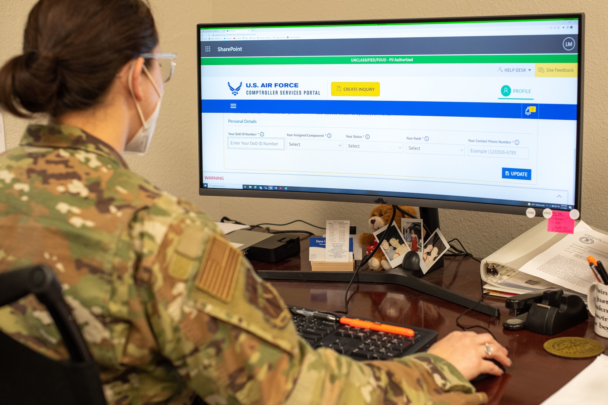 An Airmen sits at their desk facing computer