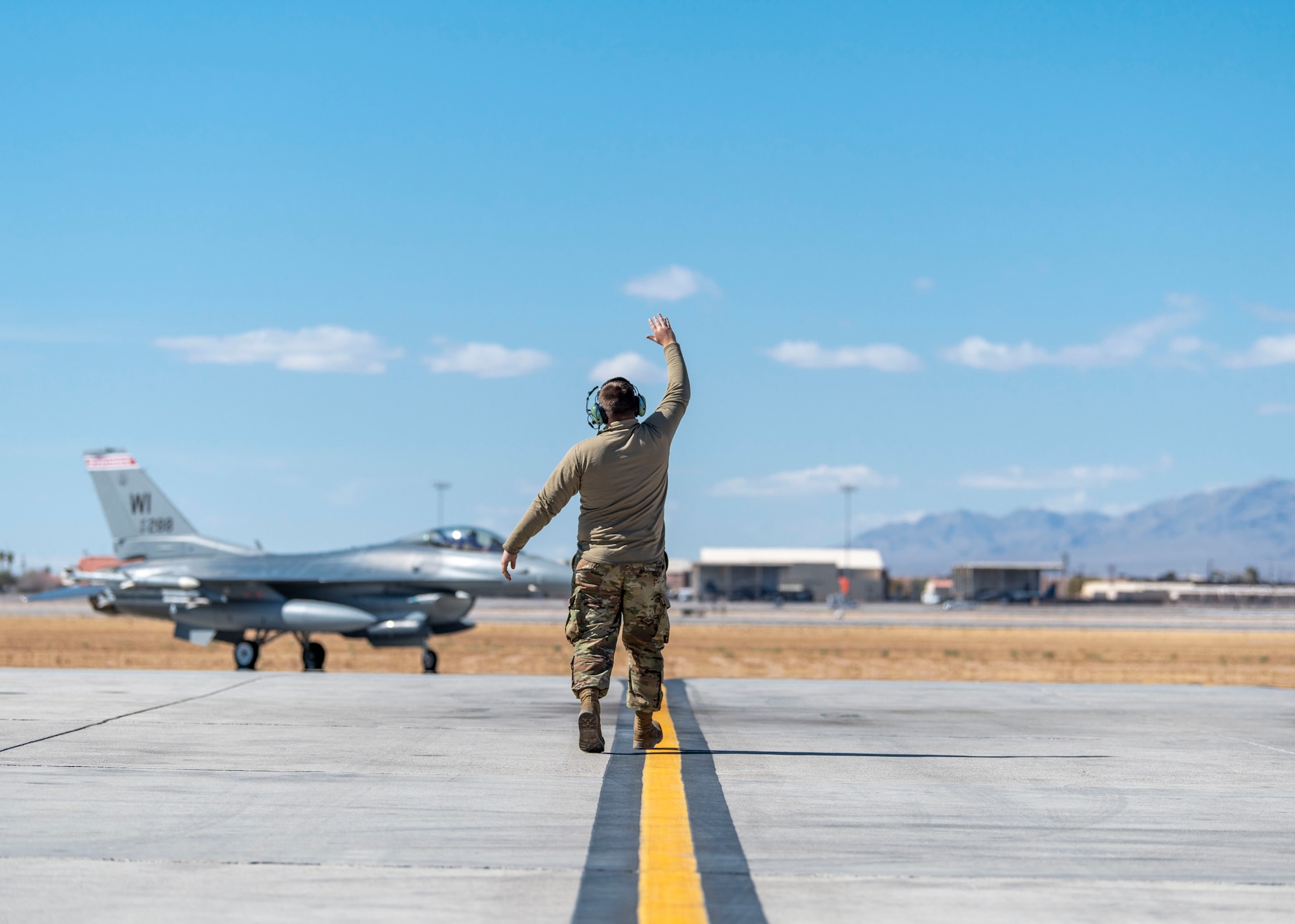 A crew chief assigned to the 115th Fighter Wing marshals and F-16 Fighting Falcon