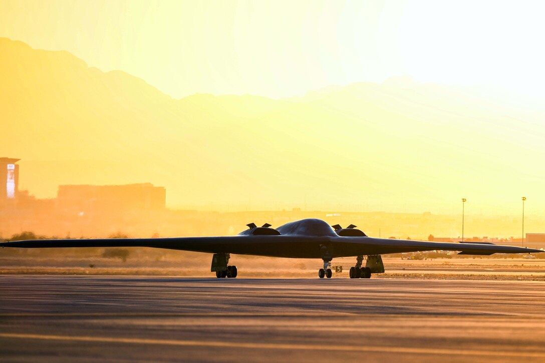 An aircraft sits on the tarmac under a sunlit sky.