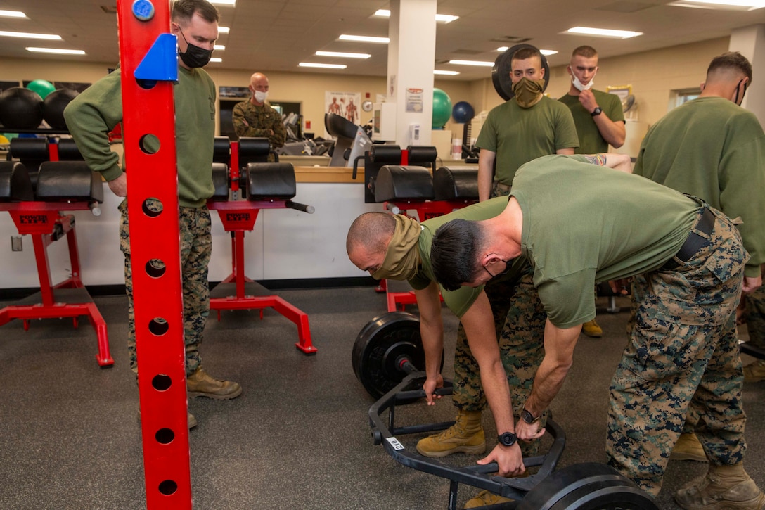 U.S. Marine Corps Staff Sgt. Jeffery Salois, an infantry Marine instructor, assists Pvt. Diego Villafanperez during a physical fitness demonstration at School of Infantry-East, Camp Lejeune, North Carolina, Jan. 11, 2022. The brief was part of a three-day Sergeant Major of the Marine Corps Force Level Summit. The summits are held quarterly to support force level sergeants major at their respective commands. (U.S. Marine Corps photo by Sgt. Victoria Ross)