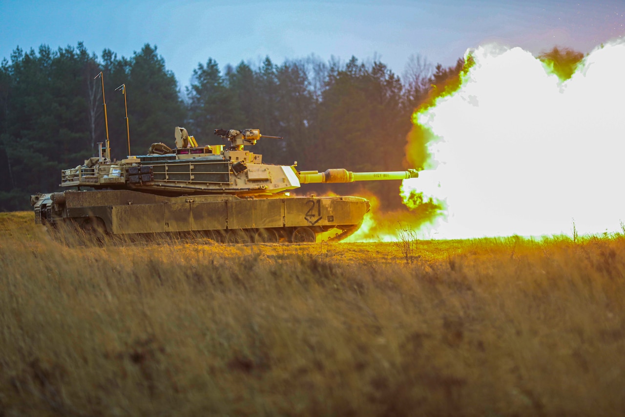 A tank fires in a field.
