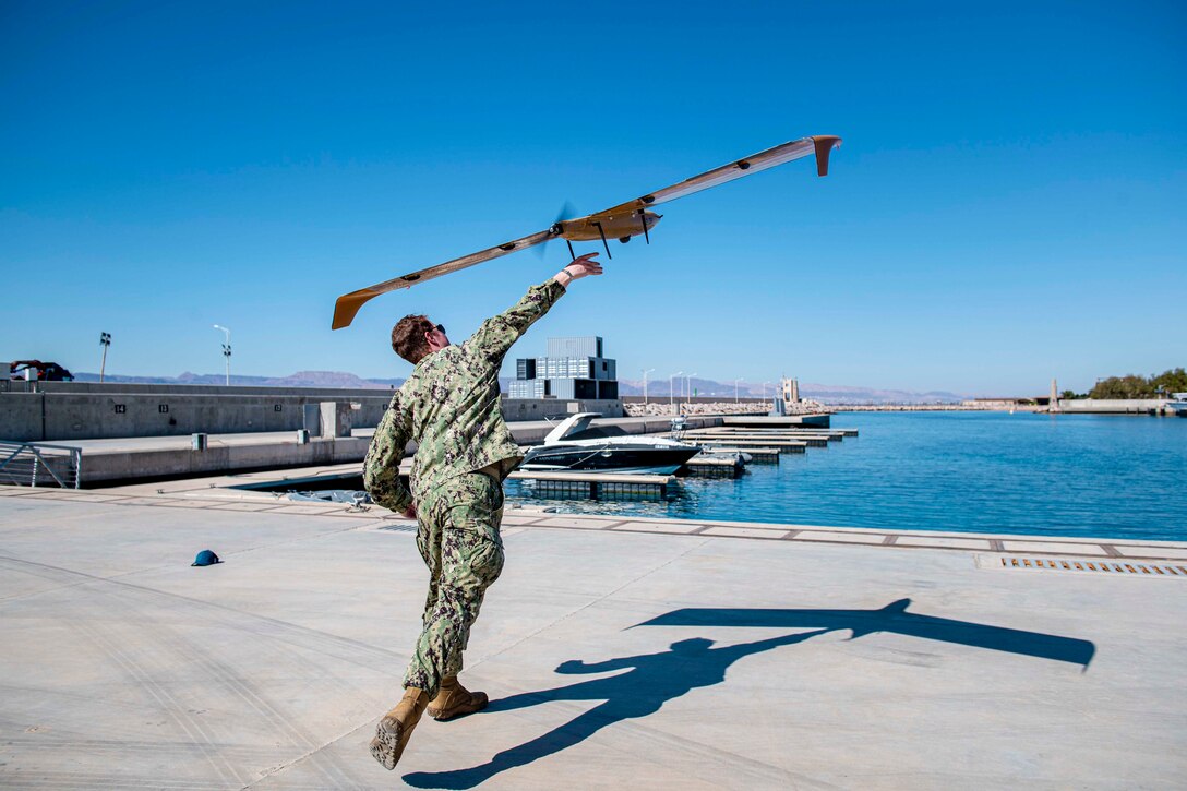 A sailor launches an unmanned aerial system.