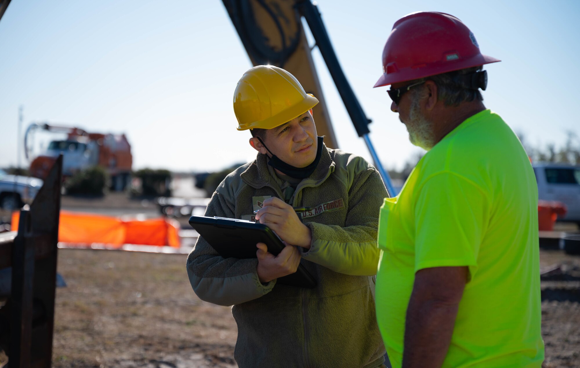An Airman talks to a construction worker at a job site.