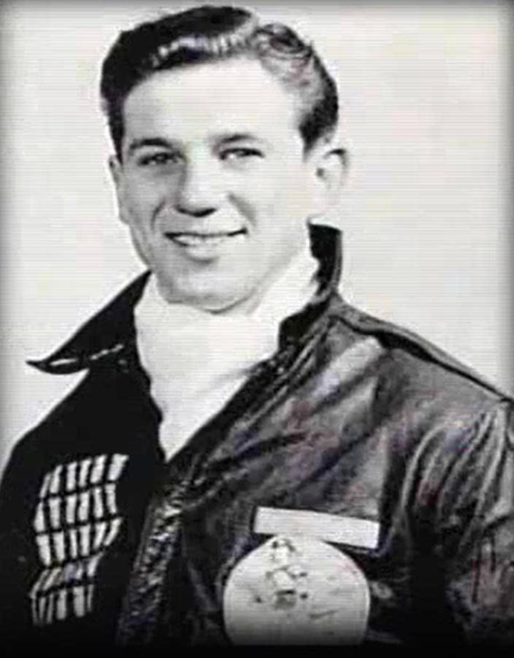 A man in a leather jacket poses for a photo.