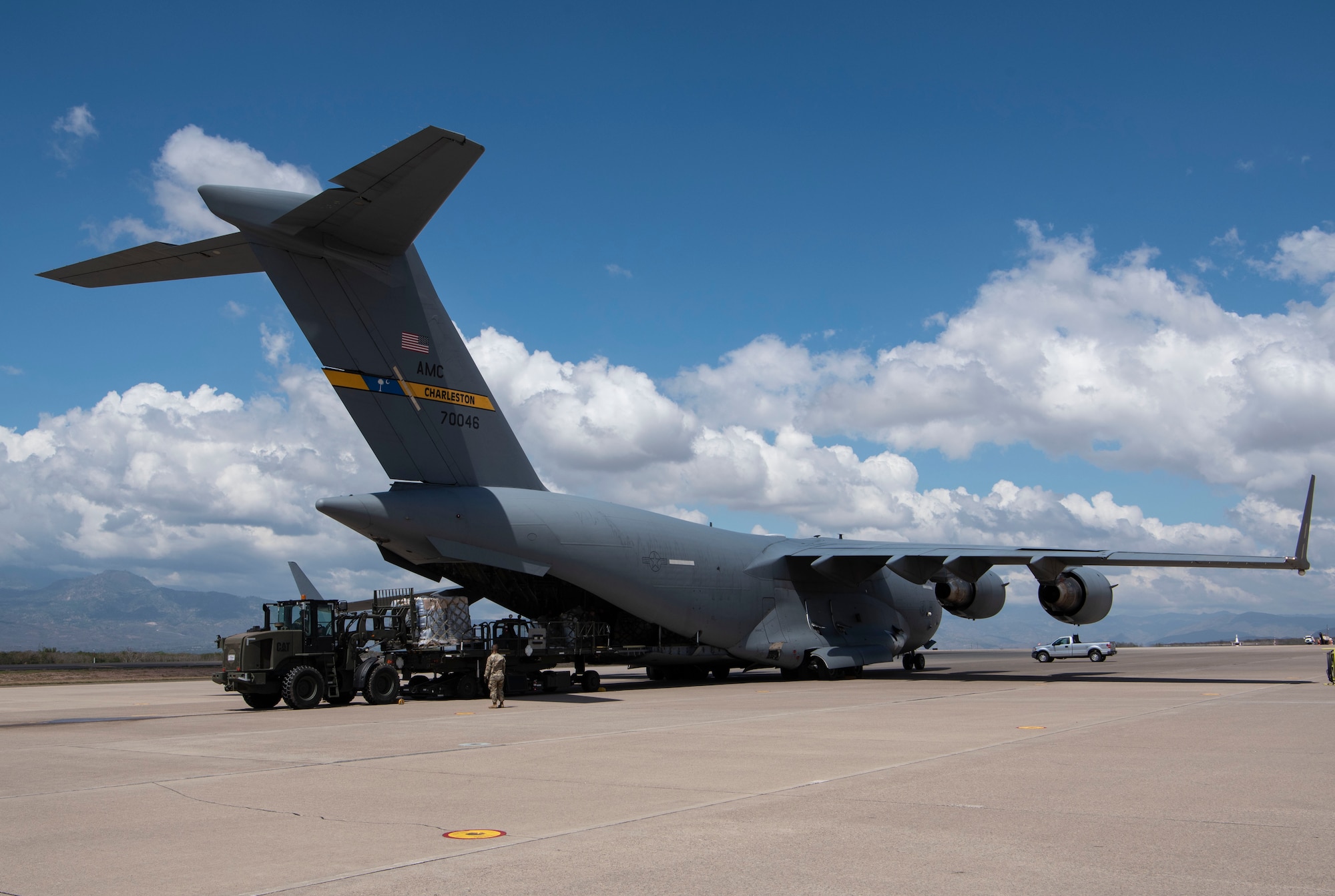 Humanitarian cargo delivered via a Charleston C-17 Globemaster III aircraft by an Air Force Reserve crew is offloaded at Soto Cano Air Base, Honduras, as part of a weekend combined aircrew training and delivery mission in Central America, Feb. 13, 2022. Cargo was donated by charities and outreach organizations throughout the U.S. and was delivered as part of the Denton Cargo Program, which allows for humanitarian donations to be carried aboard U.S. military aircraft on a space-available basis. (U.S. Air Force photo by Lt. Col. Wayne Capps)