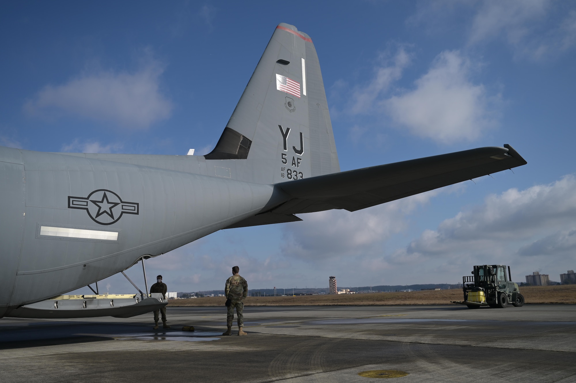 Airmen from the 374th Logistics Readiness Squadron wait to load cargo on a C-130J Super Hercules on the flightline at Yokota Air Base, Japan, during exercise Tomodachi Rescue 22 Feb. 11, 2022.