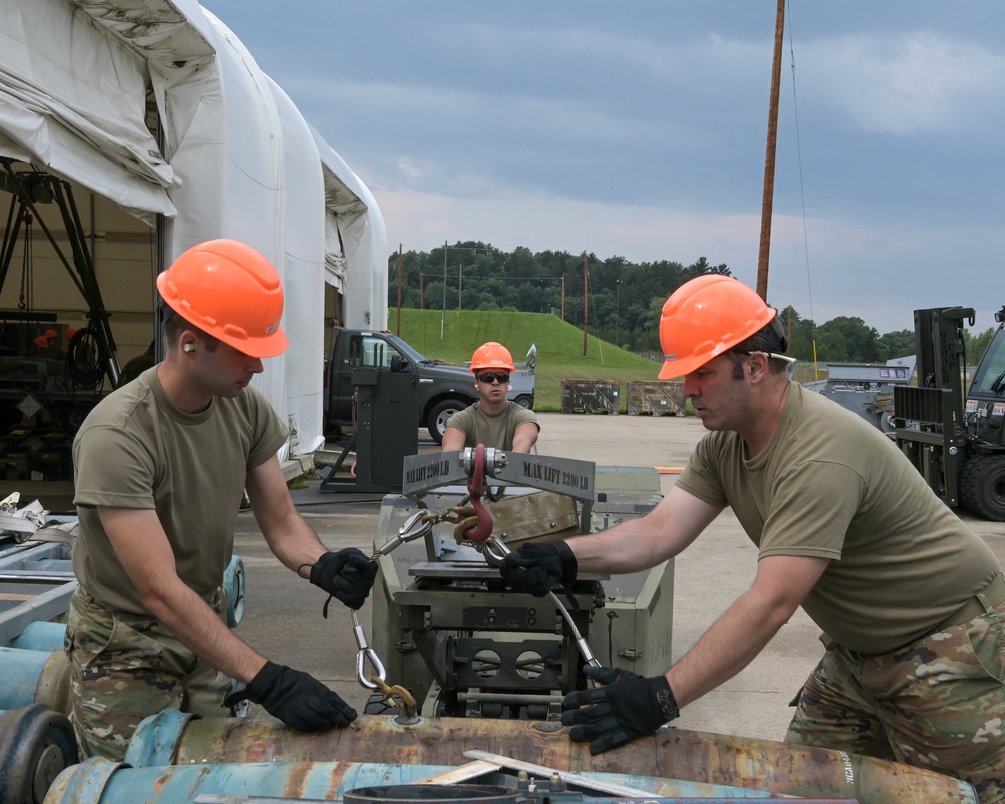 U.S Air Force munitions systems technicians assigned to the Wisconsin Air National Guard's 115th Fighter Wing, Truax Field, Madison, Wisconsin, the Idaho Air National Guard's 124th Fighter Wing, Gowen Field Air National Guard Base, Boise, Idaho, and Florida Air National Guard's 125th Fighter Wing, Jacksonville Air National Guard Base, Florida, lift an inert training bomb with an MJ-1 Jammer July 27, 2021 during the Ammo Rodeo at Volk Field Air National Guard Base, Wisconsin. The Ammo Rodeo is a joint training that consists of 22 Air National Guard and Air Force Reserve units. (U.S. Air National Guard photo by Staff Sgt. Cameron Lewis)