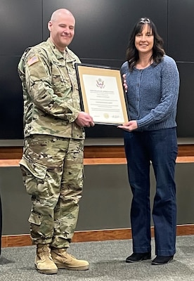 Jessica Sawyer, of Anna, Illinois, accepts a Certificate of Appreciation from husband, Staff Sgt. Phillip Sawyer, 2nd Battalion, 129th Regiment (Regional Training Institute), during his retirement ceremony Feb. 12 at Camp Lincoln, Springfield, Illinois.