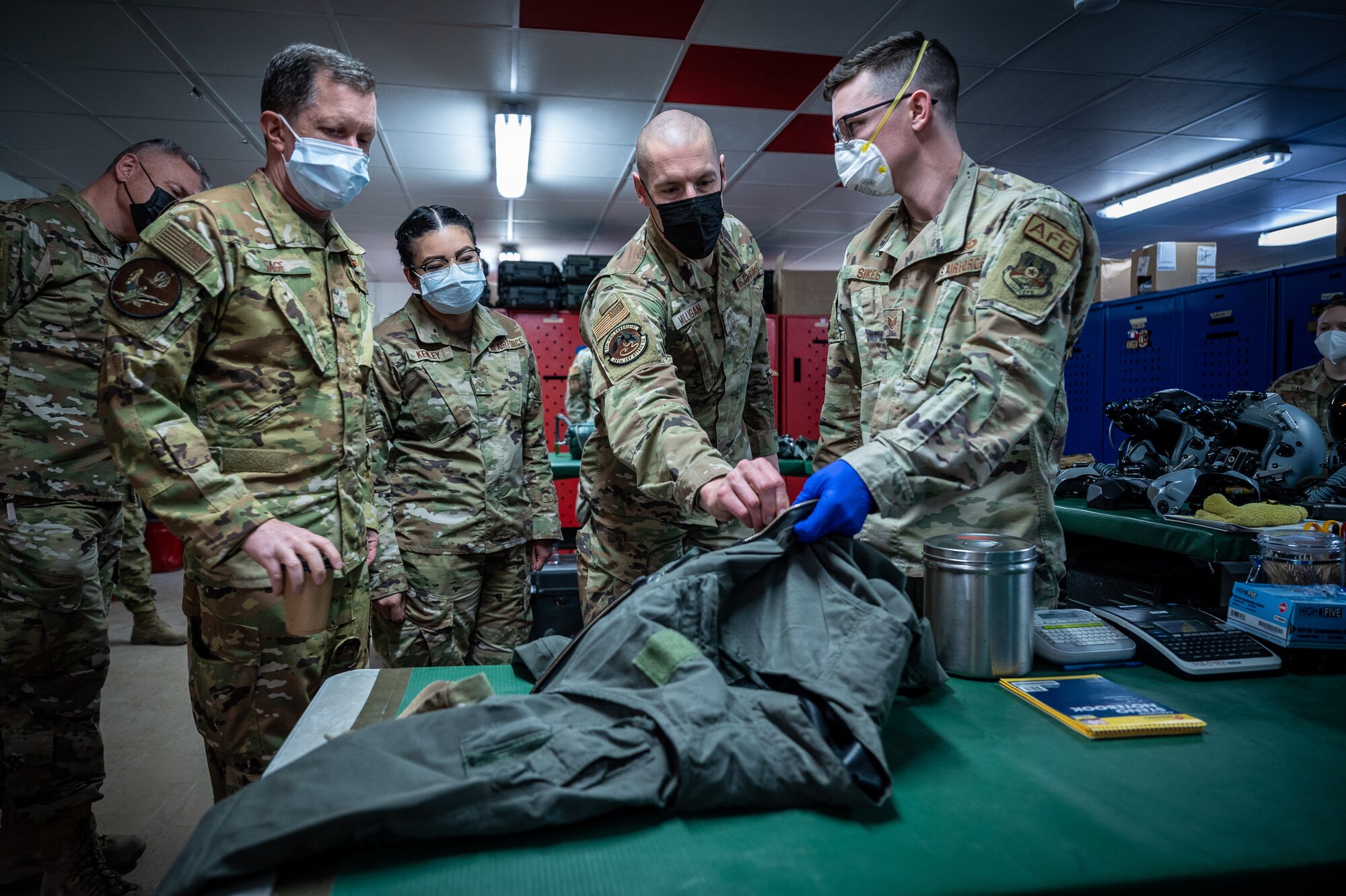 U.S. Air Force Brig. Gen. Christopher Sage, 322d Air Expeditionary Wing commander and Chief Master Sgt. Sean Milligan, command chief, along with Wing Staff members listen to Staff Sgt. Jordan Sikes, 55th Expeditionary Fighter Squadron aircrew flight equipment shift lead, as he provides an overview of aircrew equipment in Southwest Asia, Feb. 12, 2022. Members of the AFE team maintain all equipment aircrew use while flying including helmets, harnesses, anti-exposure dry suits, survival vests, night vision goggles and more. Additionally, AFE Airmen also service parachutes and survival kits that are loaded onto the aircraft. (U.S. Air Force photo by Master Sgt. Christopher Parr)