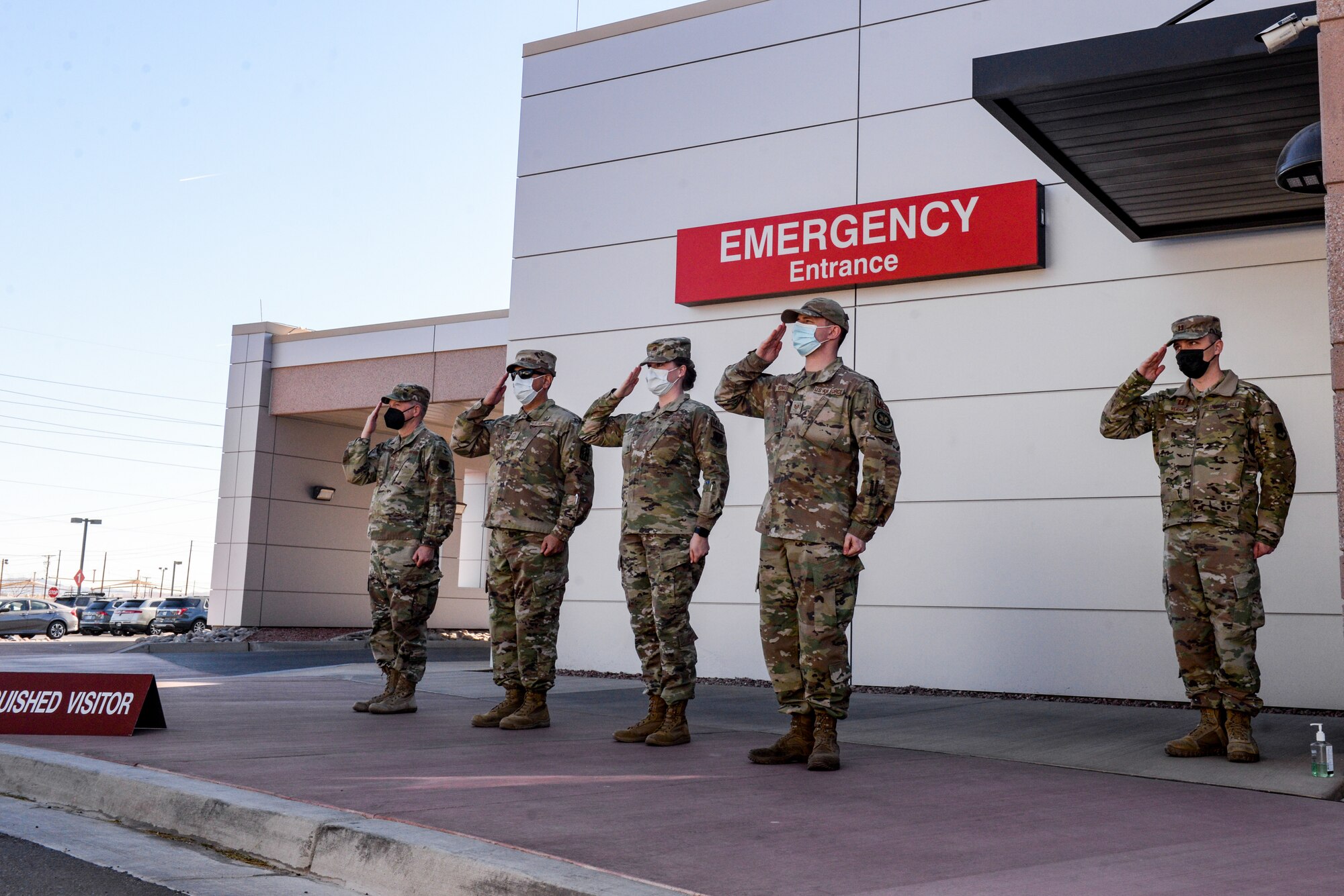 Airmen salute in front of emergency room