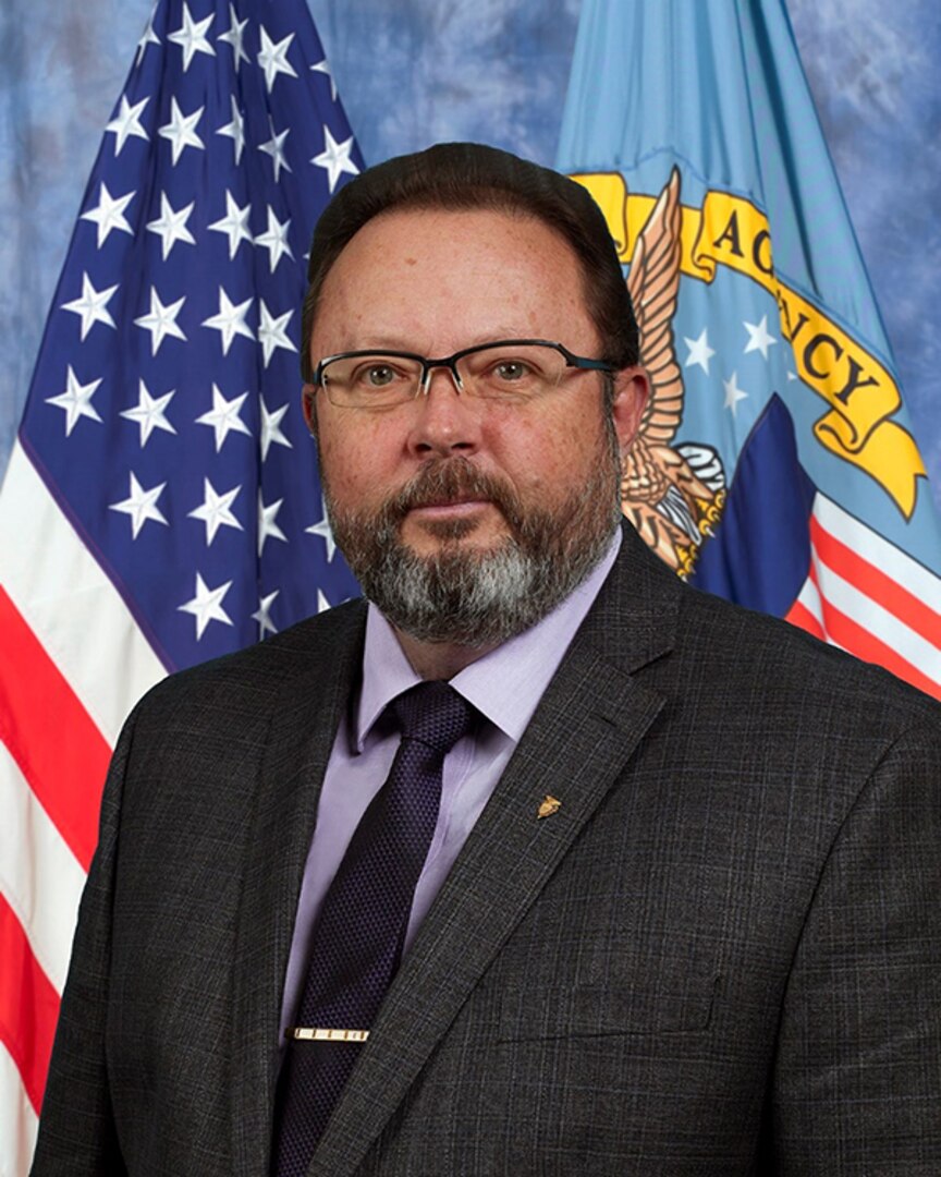 Portrait of a man in front of flags.