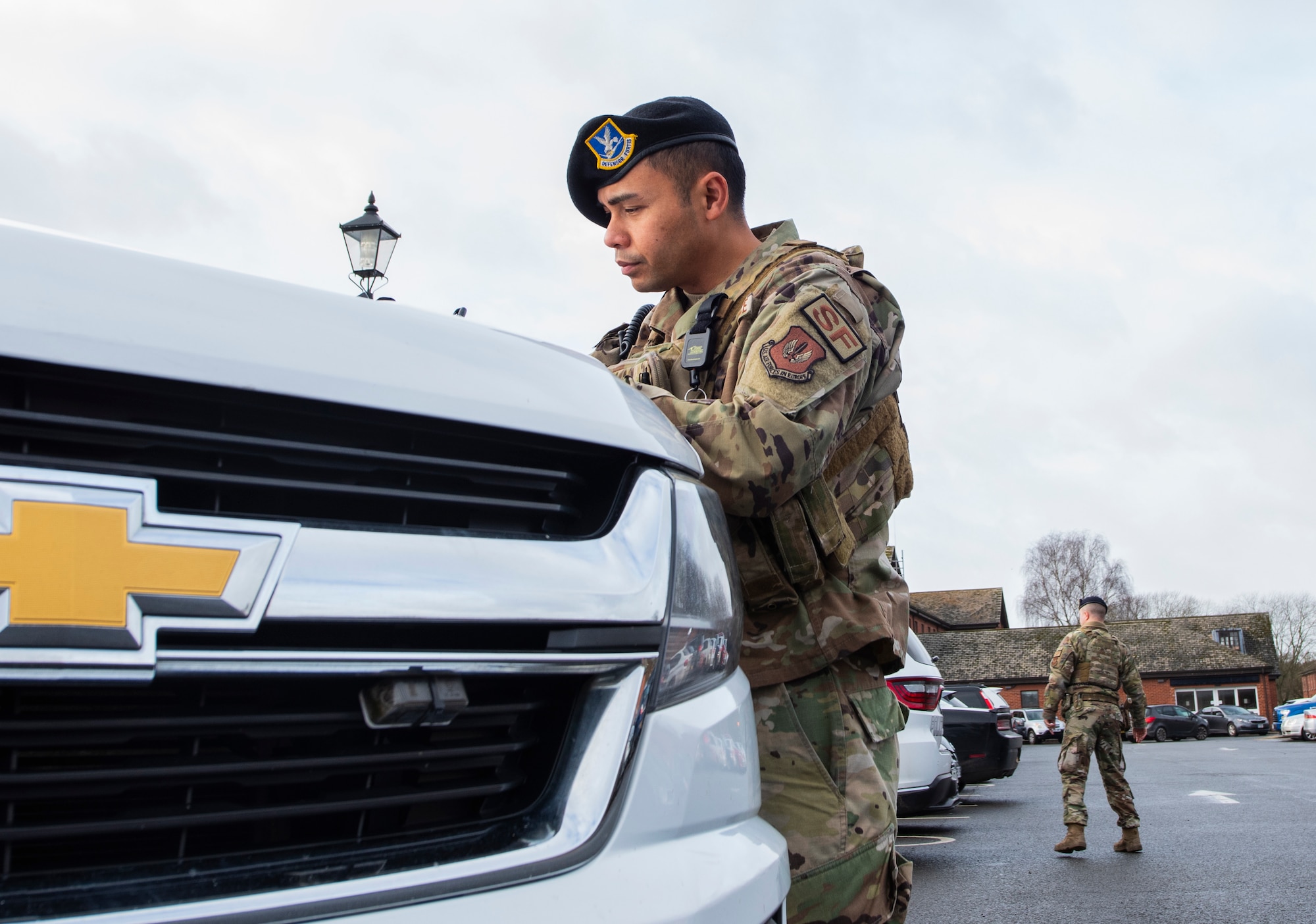 U.S. Air Force Tech. Sgt. Randy Roquid, 100th Security Forces Squadron flight sergeant, prepares parking tickets for illegally parked vehicles while Tech Sgt. Thomas Hartline, 100th SFS flight sergeant, watches for traffic on Royal Air Force Mildenhall, England, Feb. 16, 2022. By strictly enforcing the use of legal parking spaces, members of the 100th SFS ensure emergency vehicles are able get where they need to be in a moment’s notice. (U.S. Air Force photo by Senior Airman Kevin Long)