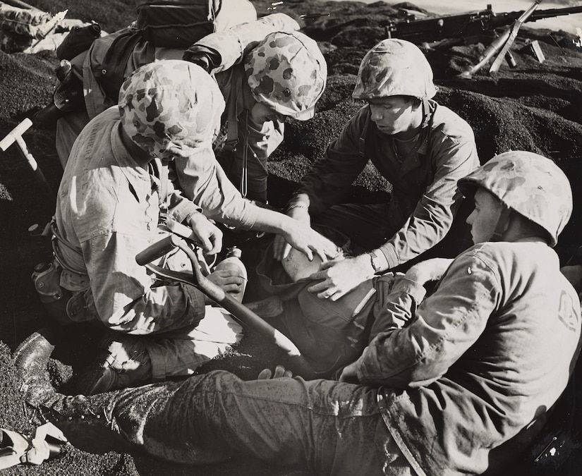 Four men work to help a fifth man lying on the ground.