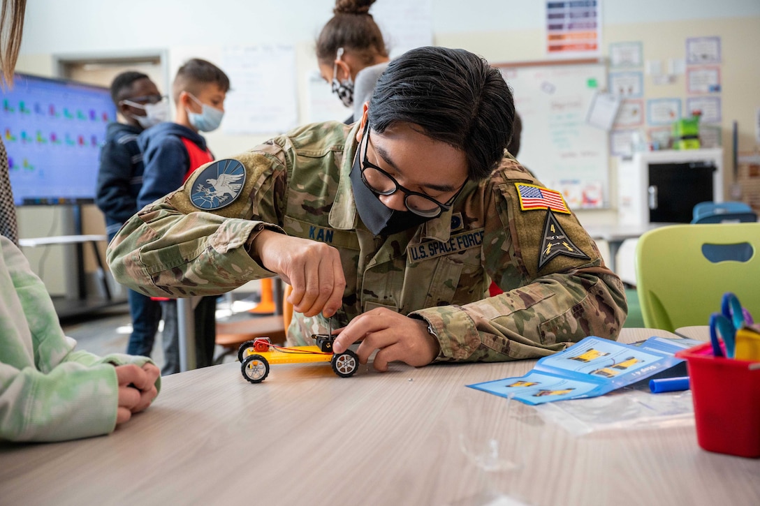 A guardian helps a student build a model car.