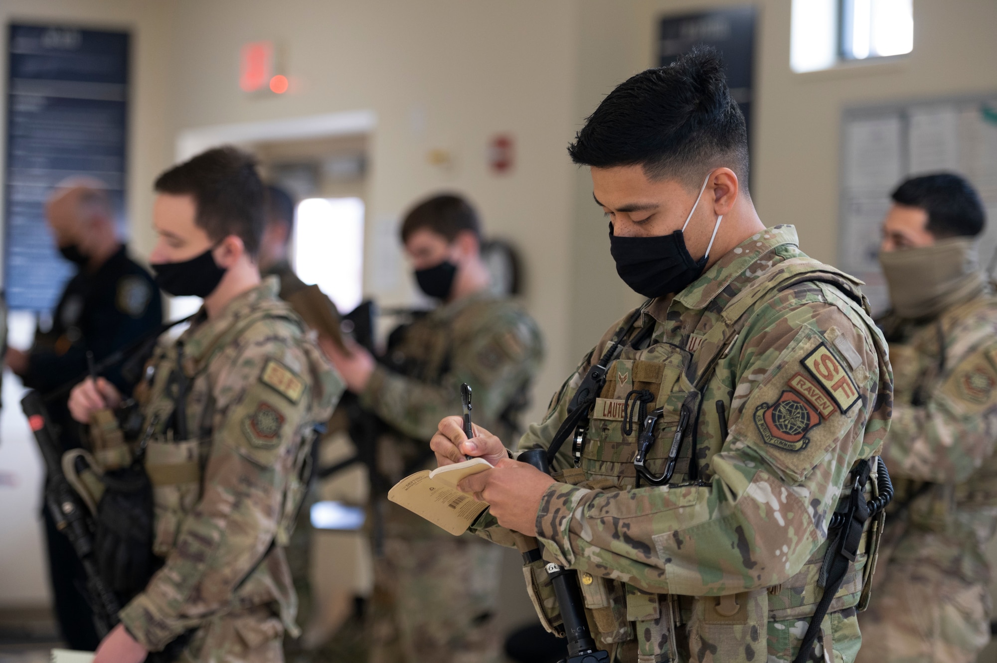 U.S. Air Force Airman 1st Class Keith Lautez, 375th Security Forces Squadron entry controller, uses a notepad to write down important information during guardmount at Scott Air Force Base, Illinois, Feb. 12, 2022. Lautez is certified as a Pheonix Raven, who are specially trained security forces personnel that provide security for Air Mobility Command aircraft transiting high terrorist and criminal threat areas. (U.S. Air Force photo by Staff Sgt. Dalton Williams)