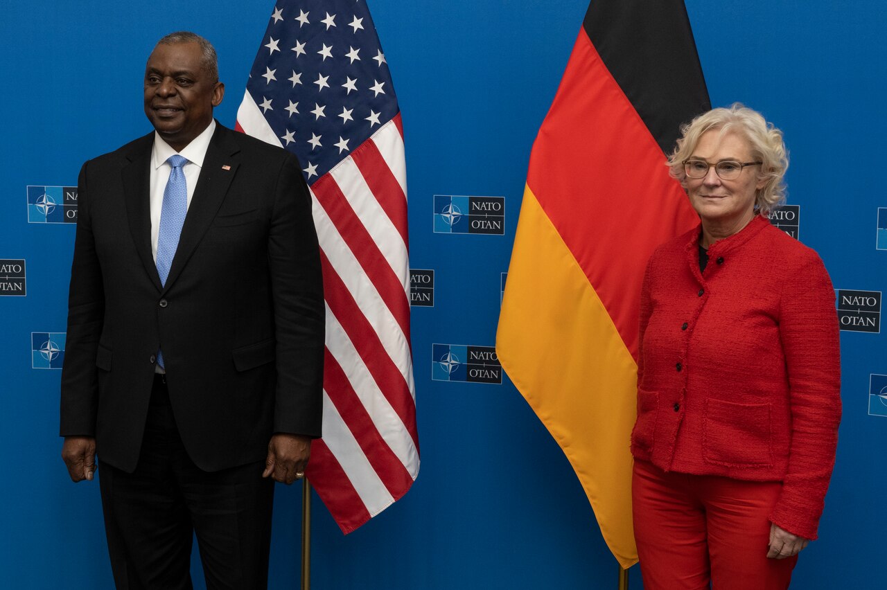 A man and women stand in front of a U.S. and German flags.