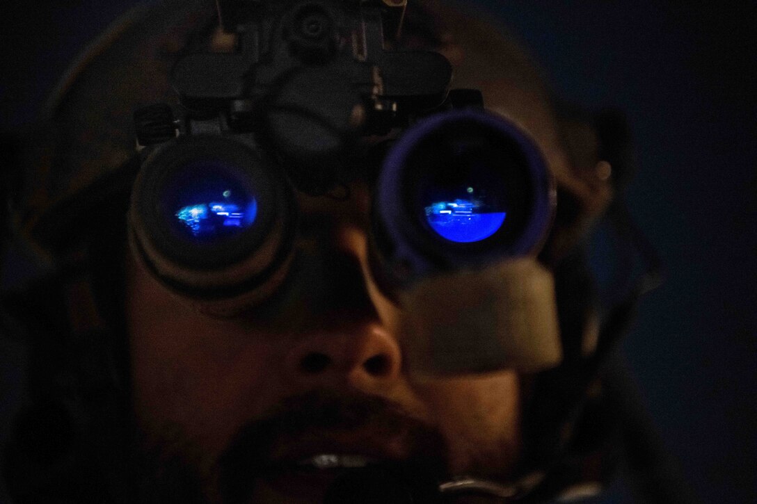 An airman wears night vision goggles that reflect blue light.