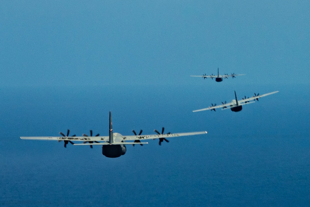 Three aircraft fly over the ocean.