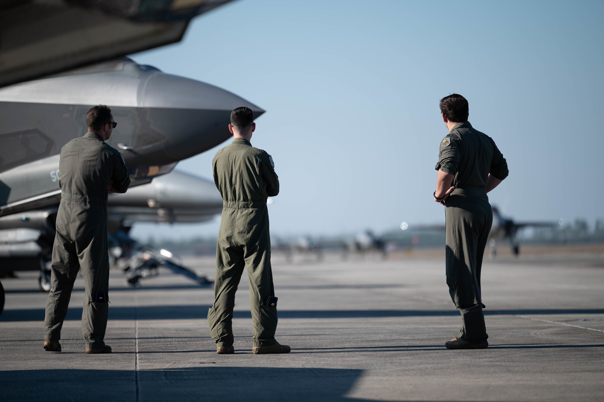 Airmen watch F-35A Lightning IIs taxi on the flight line.