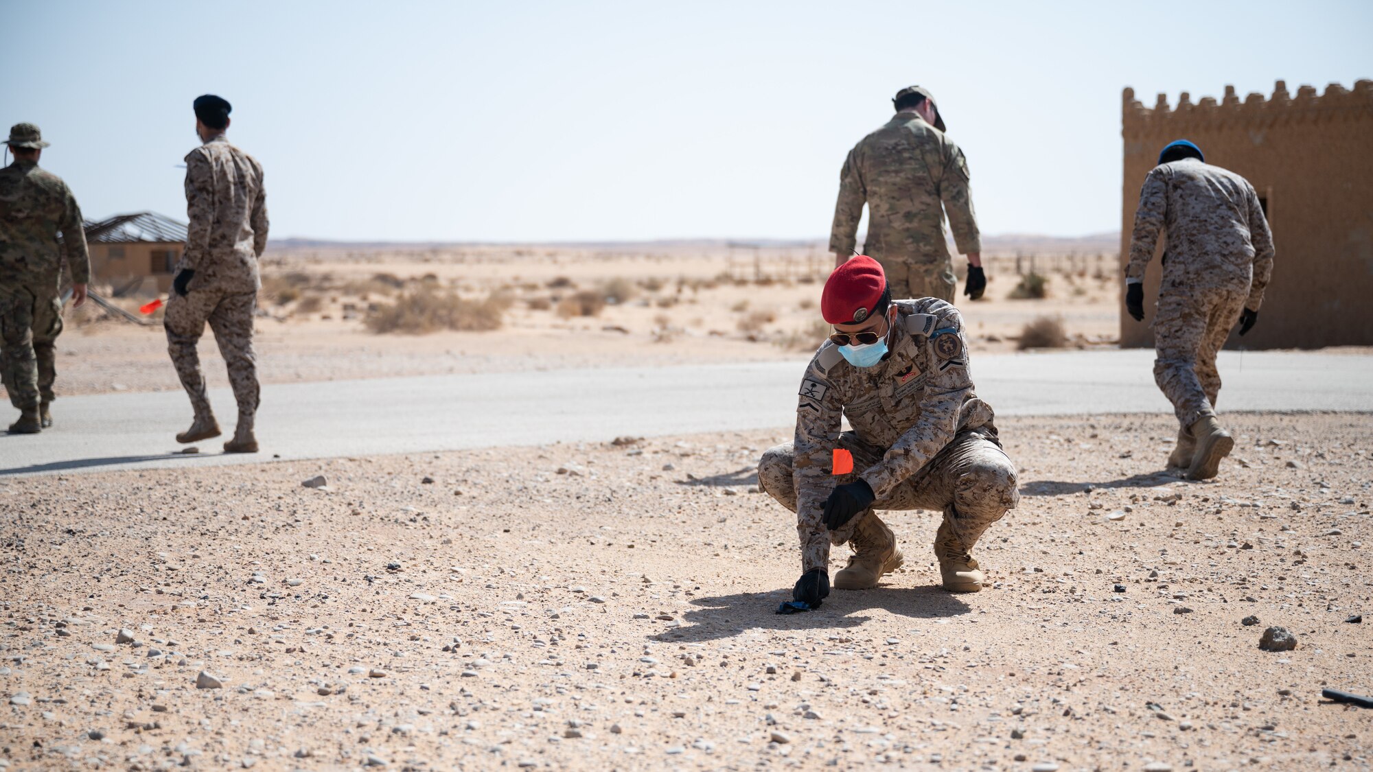 A service member from the Royal Saudi Air Force places a flag near a simulated piece of evidence during a bilateral training exercise between the RSAF and U.S. Air Force at Prince Sultan Air Base, Kingdom of Saudi Arabia, Feb. 10, 2021. The exercise provided exposure to explosive ordnance disposal process when identifying and neutralizing a blast threat, rendering the area safe and post blast investigations processes. (U.S. Air Force photo by Senior Airman Jacob B. Wrightsman)