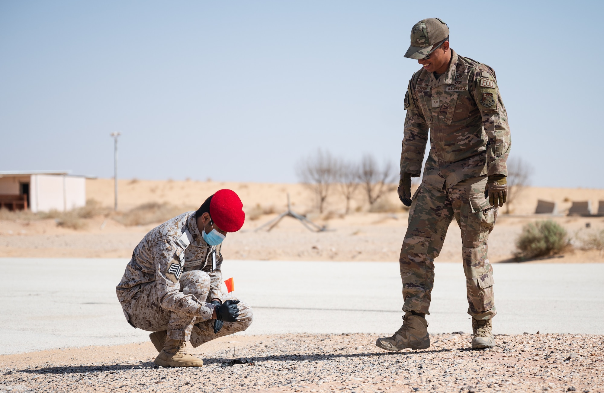 Service members from the Royal Saudi Air Force and the U.S. Air Force place a flag near a simulated piece of evidence during a bilateral training exercise at Prince Sultan Air Base, Kingdom of Saudi Arabia, Feb. 10, 2022. Using the expertise of the EOD team and the Office of Special Investigation Expeditionary Detachment 2419, the teams went through the steps of investigating and collecting evidence after the scene of an explosion. (U.S. Air Force photo by Senior Airman Jacob B. Wrightsman)