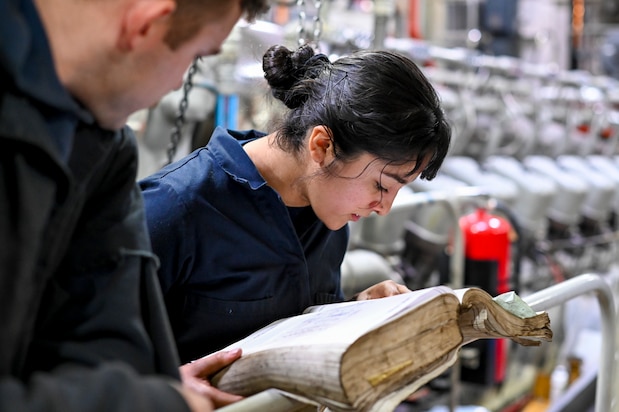 Coast Guard Machinery Technician Third Class Joanalicia Ramirez looks up the codes for the next parts to gather as she works with her unit to build an engine on a cutter moored at Base Portsmouth, Nov. 16, 2021, in Portsmouth, Virginia. The unit, called the Maintenance Augmentation Team, or MAT, provides mechanical and maintenance support for the cutters in the area. (U.S. Coast Guard photo by Petty Officer Third Class Emily Velez)