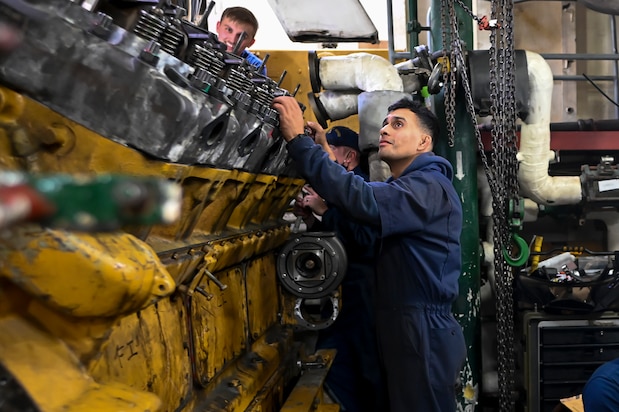 Coast Guard Machinery Technician Third Class Miguel Caceres works with his unit to build an engine on a cutter moored at Base Portsmouth, Nov. 16, 2021, in Portsmouth, Virginia. The unit, called the Maintenance Augmentation Team, or MAT, provides mechanical and maintenance support for the cutters in the area. (U.S. Coast Guard photo by Petty Officer Third Class Emily Velez)