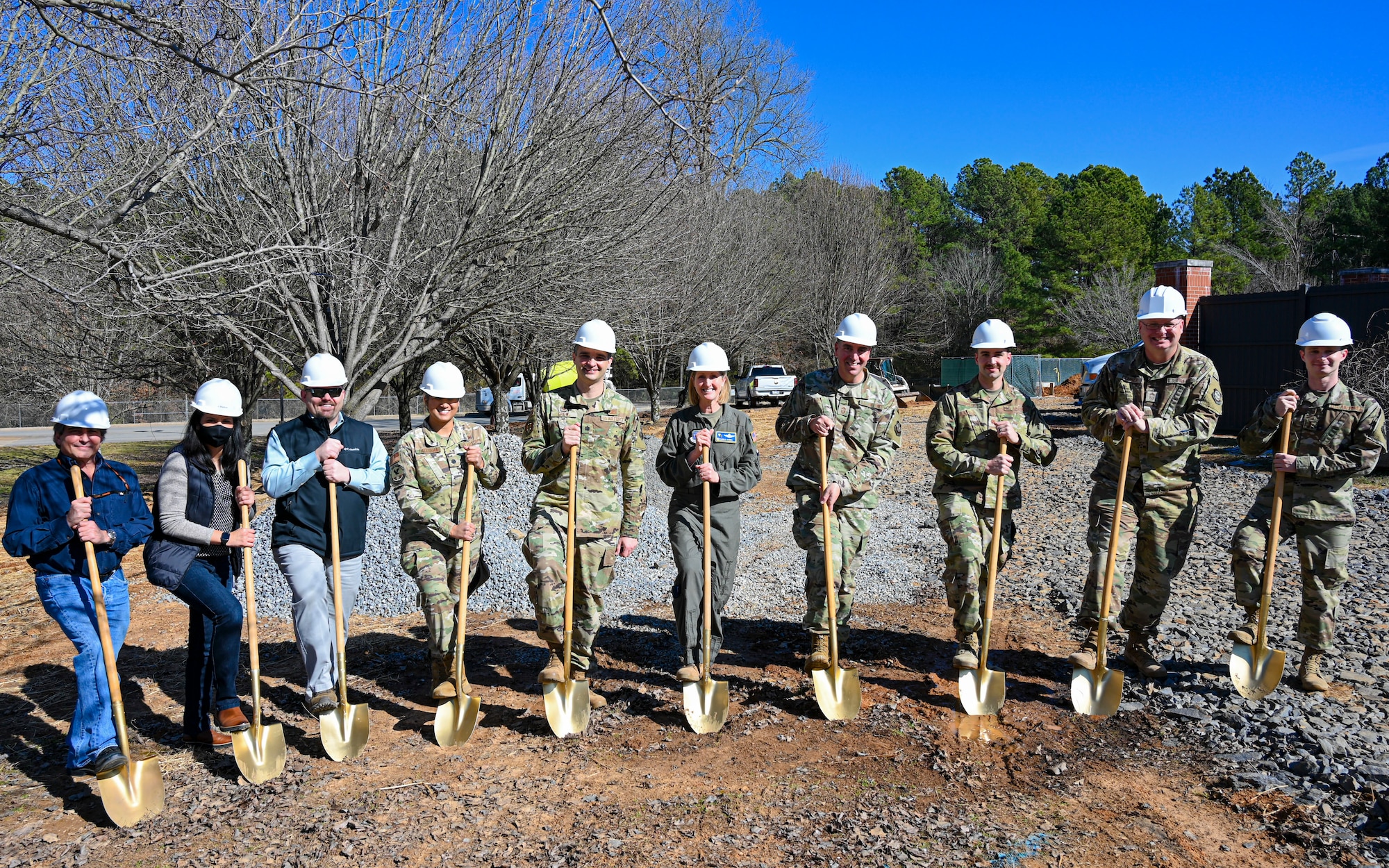 Airmen pose for a photo with golden shovels during a groundbreaking ceremony.