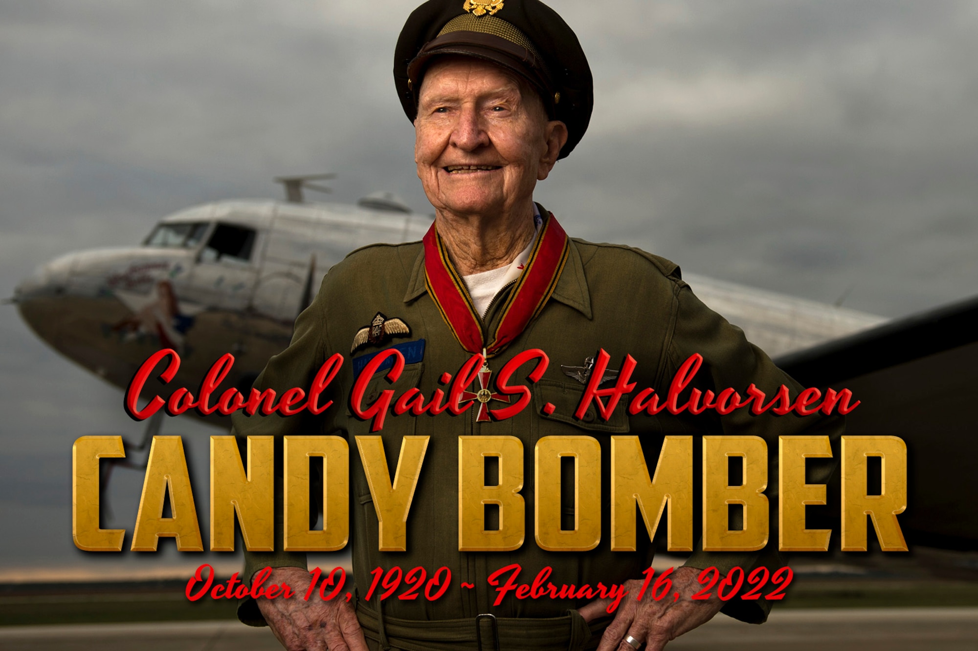 The Candy Bomber poses in front of an aircraft while the words Col. Gail S. Halovrsen, Candy Bomber, October 10, 1920-February 16, 2022, appear at the bottom of the image.