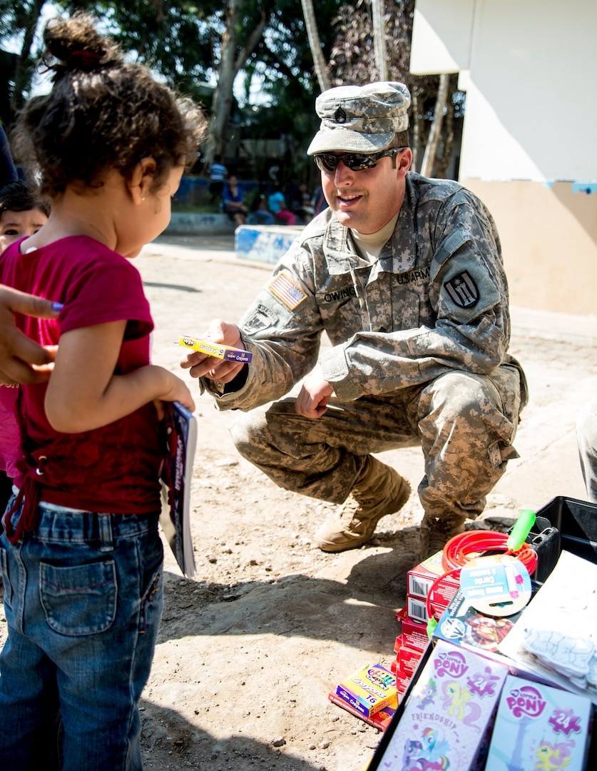 Staff Sgt. Adam Owings from Mankato, Minn., a construction supervisor with the 492nd Engineer Company also out of Mankato, hands a local child a package of crayons during this year's Beyond the Horizon mission. BTH is a humanitarian and civic assistance exercise that lasts for several months and provides construction and medical assistance to the people of El Salvador. (U.S. Army photo by Staff Sgt. Cliff Coy)
