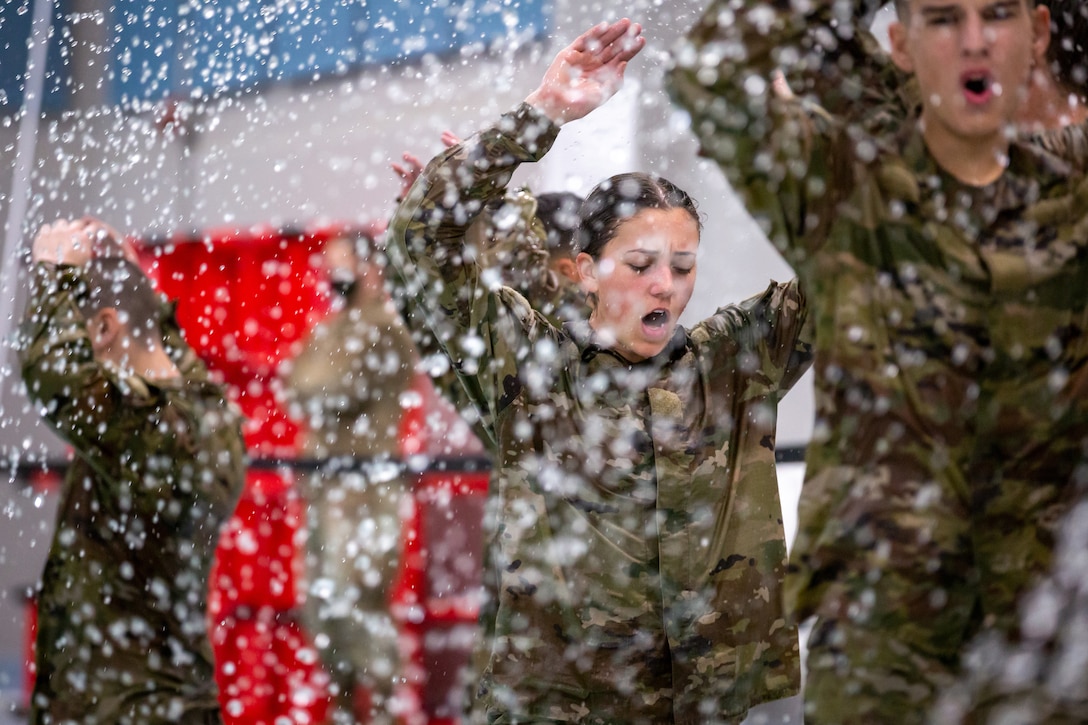 Cadets stand in a room with water coming from above them.