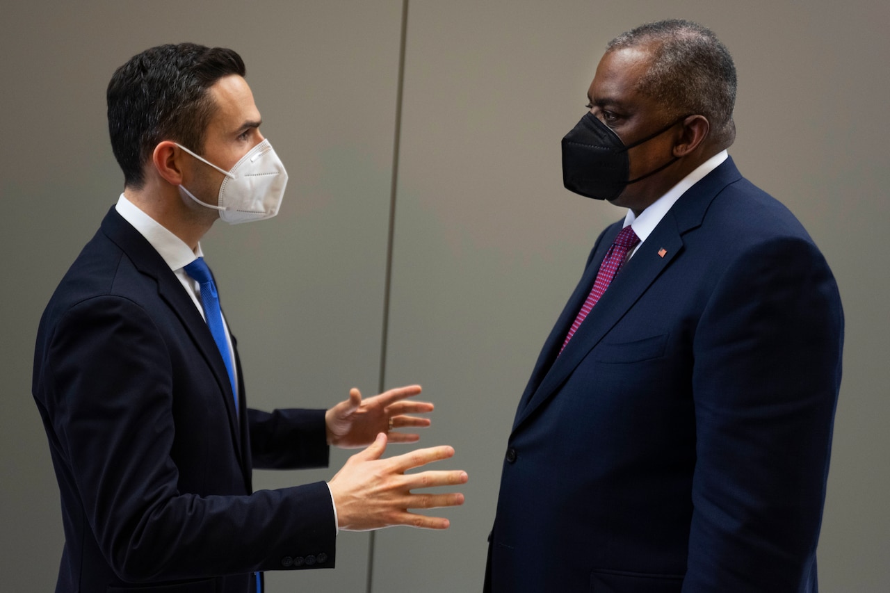 A civilian gestures while speaking to Secretary of Defense Lloyd J. Austin III.