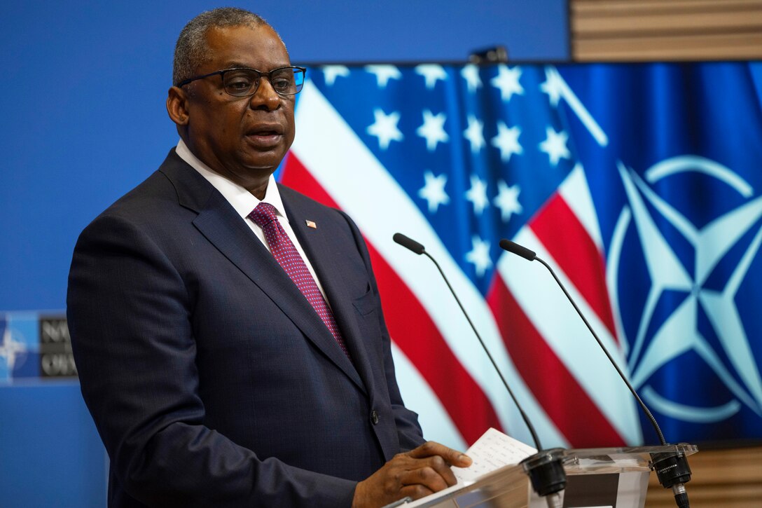 Defense Secretary Lloyd J. Austin III stands and speaks at a lectern with two microphones.