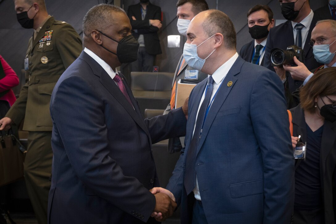 Secretary of Defense Lloyd J. Austin III shakes hands with another official.