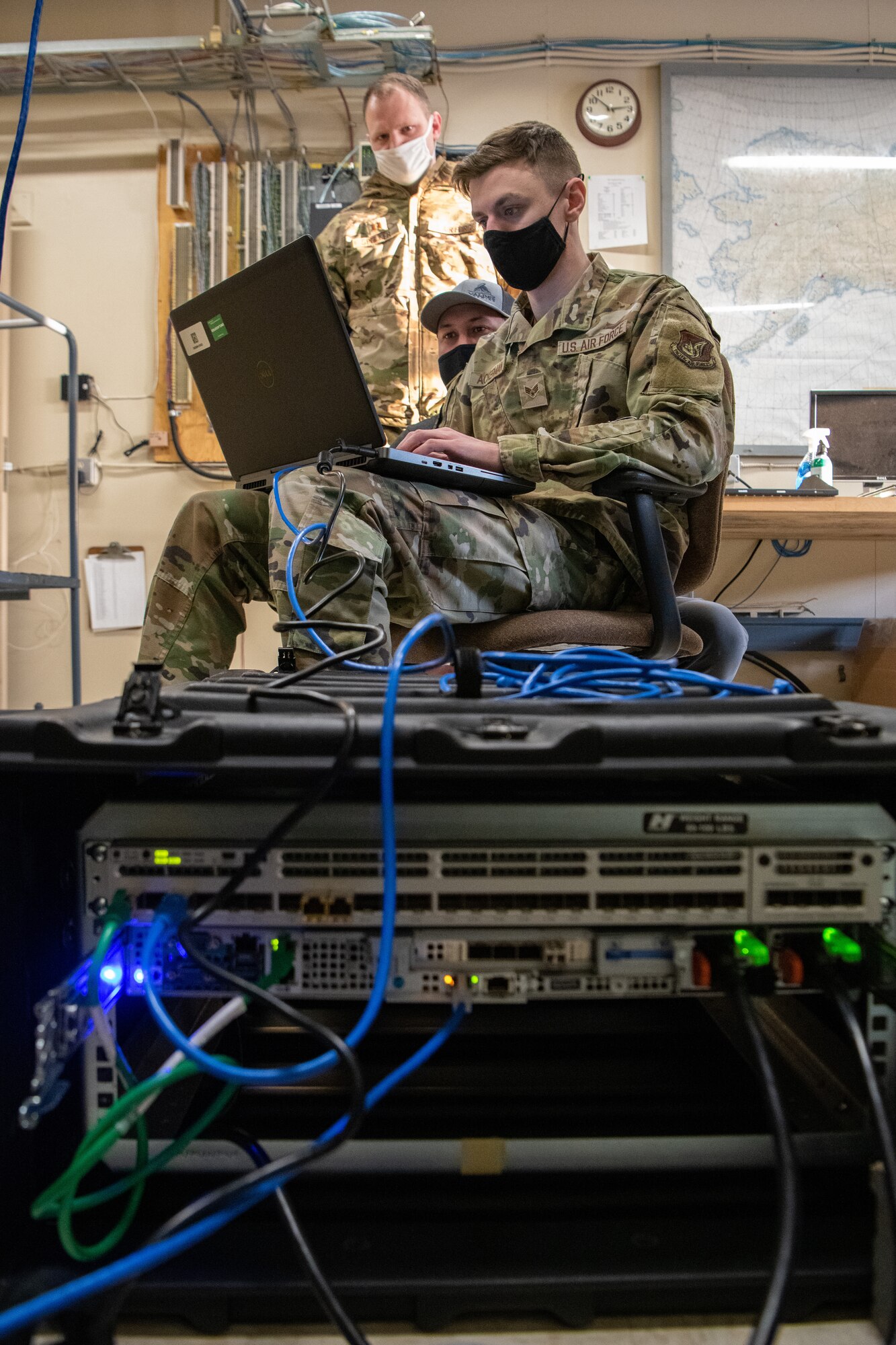 U.S. Air Force Capt. Jake Spuller, left, the 611th Air Communications Squadron Special Missions Flight Commander; Brandon Baldwin, center, 611th ACOMS Mission Defense Team System Administrator; and Senior Airman Samuel Ackerman, right, a 611th ACOMS Mission Defense Team operator, perform cybersecurity measures.