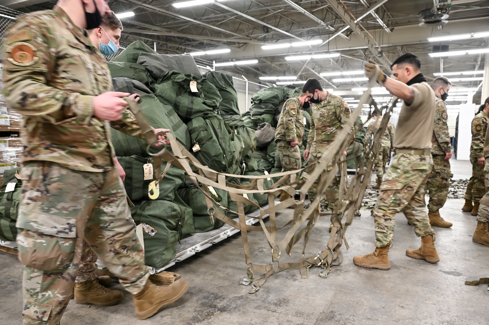 Airmen from 75th Logistics Readiness Squadron and 388th Fighter Wing and gather straps to wrap around mobility bags on pallets Feb. 17, 2022, at Hill Air Force Base, Utah. Airmen from the active duty 388th and Reserve 419th Fighter Wings were deployed with F-35A Lightning II aircraft to Spangdahlem Air Base, Germany, to bolster readiness and enhance NATO’s collective defensive posture. (U.S. Air Force photo by Cynthia Griggs)