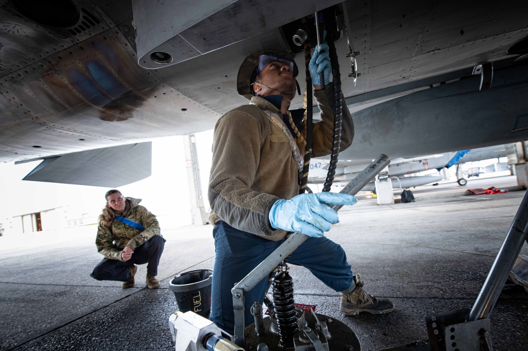 Two maintainers check oil for F-15.