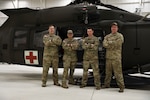 Alaska Army National Guard Chief Warrant Officer 2 Bradley Jorgensen, Sgt. 1st Class Damion Minchaca, Capt. Cody McKinney, and Staff Sgt. Sonny Cooper, all members of Golf Company, 2-211th General Support Aviation Battalion, in front of an HH-60M Black Hawk helicopter at Bryant Army Airfield on Joint Base Elmendorf-Richardson, Feb. 17, 2022. The crew received the DUSTOFF Association 2021 Rescue of the Year award for their efforts in a rescue completed Sept. 15, 2021.
